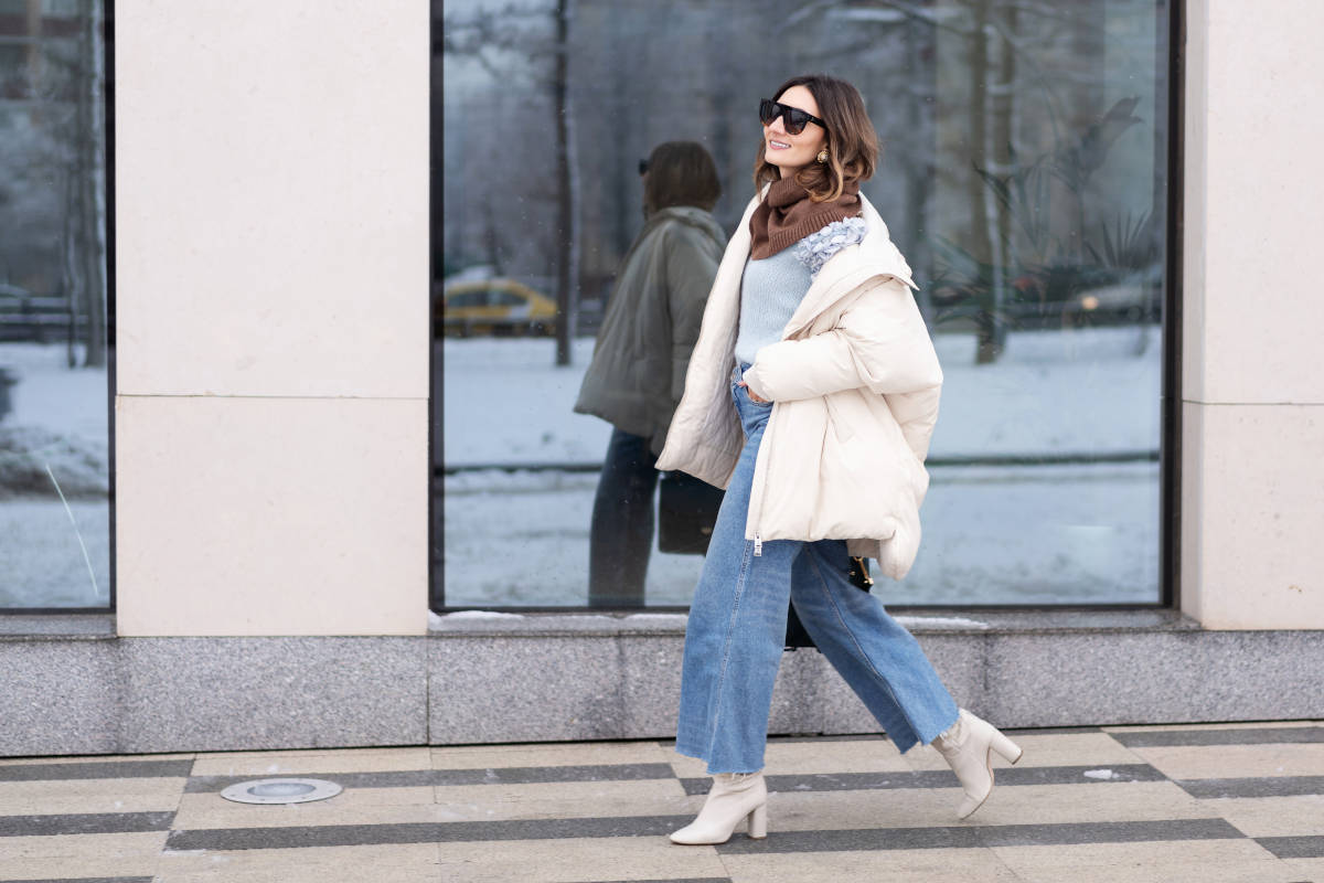 modella passeggia piumino bianco oversize stivaletti bianchi jeans