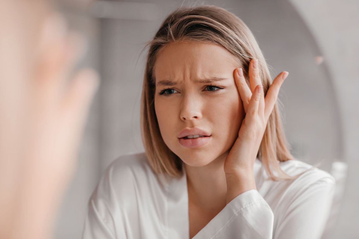 Ragazza che si guarda allo specchio il viso