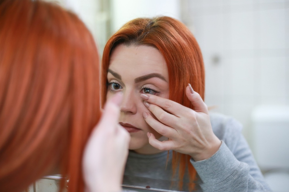 Ragazza capelli rossi mette lenti a contatto
