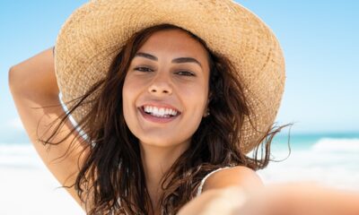 Ragazza sorridente con cappello di paglia sulla spiaggia