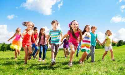 Bambini sorridenti che corrono su un prato in primavera