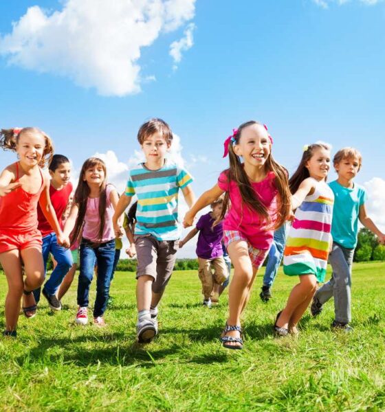 Bambini sorridenti che corrono su un prato in primavera
