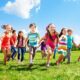 Bambini sorridenti che corrono su un prato in primavera