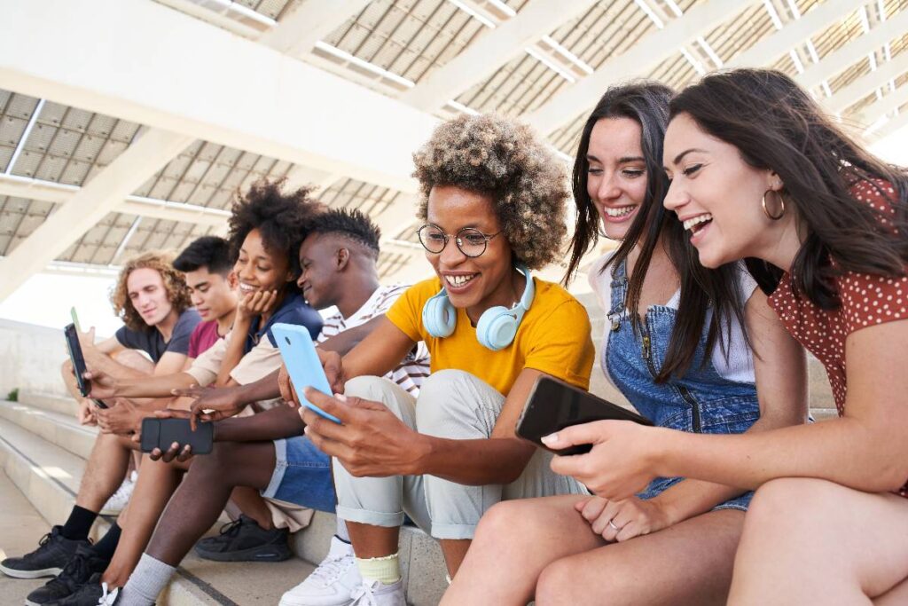 Amici insieme mentre usano i social sul telefono