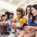 Amici insieme mentre usano i social sul telefono