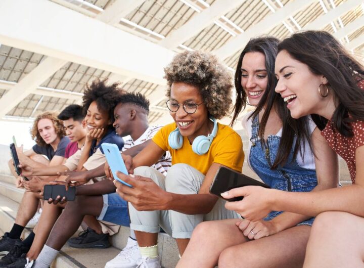 Amici insieme mentre usano i social sul telefono