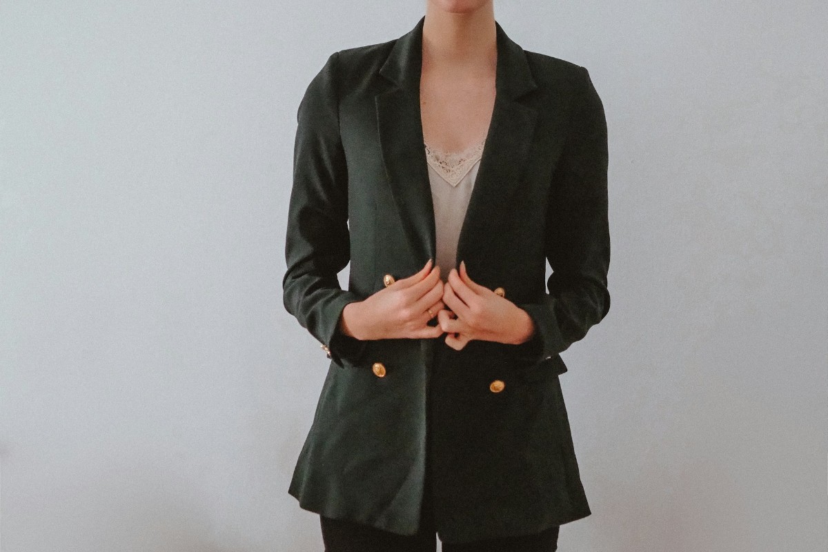 Donna con blazer verde scuro e bottoni dorati.