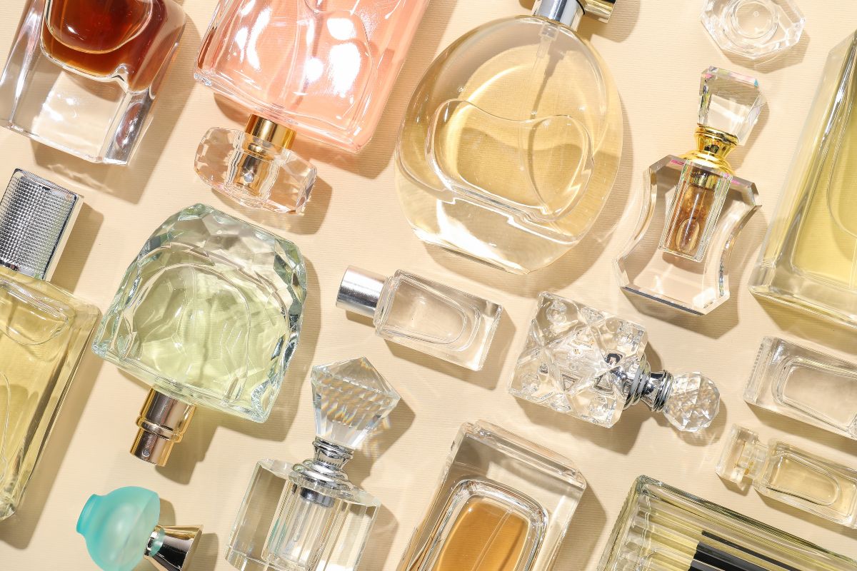 Estetica vivace: flaconi di profumo di vari colori e design disposti su un fondo giallo pastello.