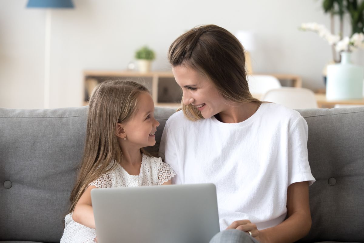 Famiglia felice guarda il computer comodamente seduta sul divano di casa.
