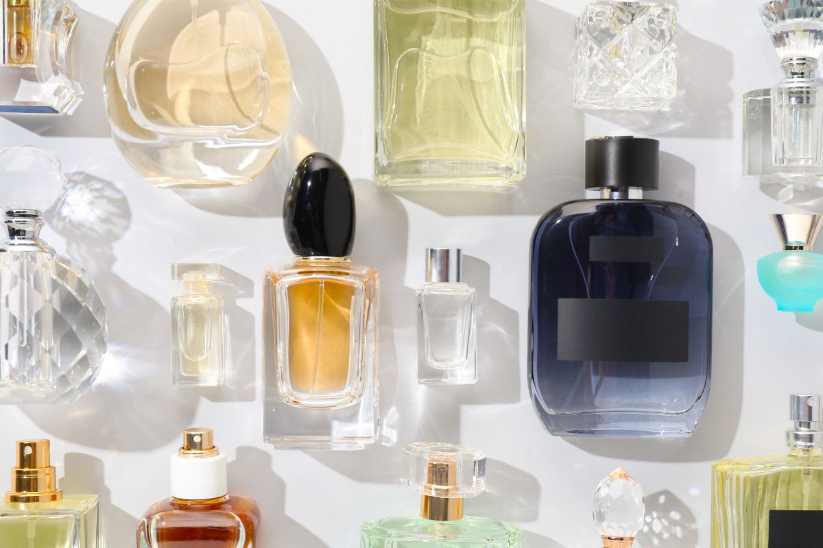 Estetica vivace: flaconi di profumo di vari colori e design disposti su un fondo giallo pastello.