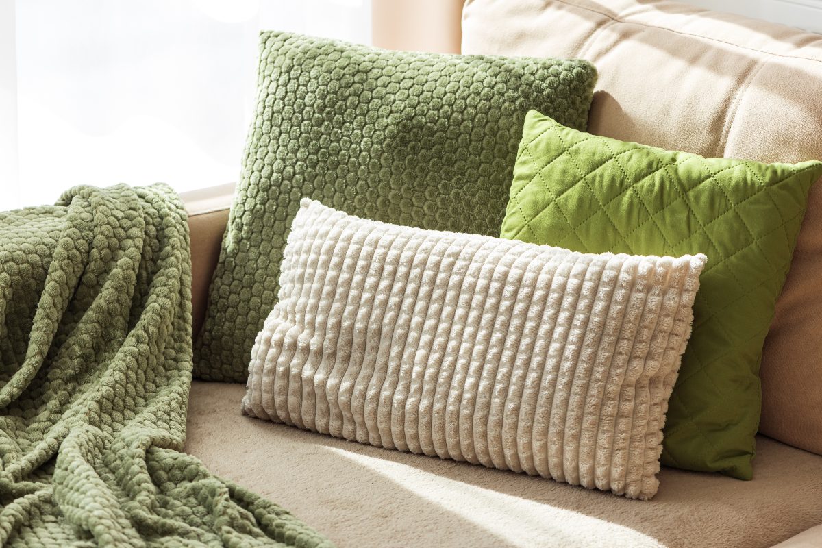 Cuscini e una coperta nelle tonalità panna e verde.